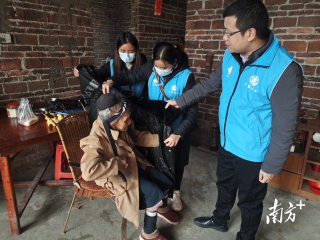 連南瑤族自治縣香坪鎮(zhèn)社工站為困難高齡老人送去御寒棉衣，并幫老人穿上棉衣。